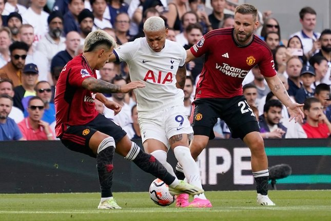 Richarlison coba diadang Lisandro Martinez dan Luke Shaw dalam laga Tottenham vs Manchester United, Sabtu (19/8/2023). (c) AP Photo/Alberto Pezzali